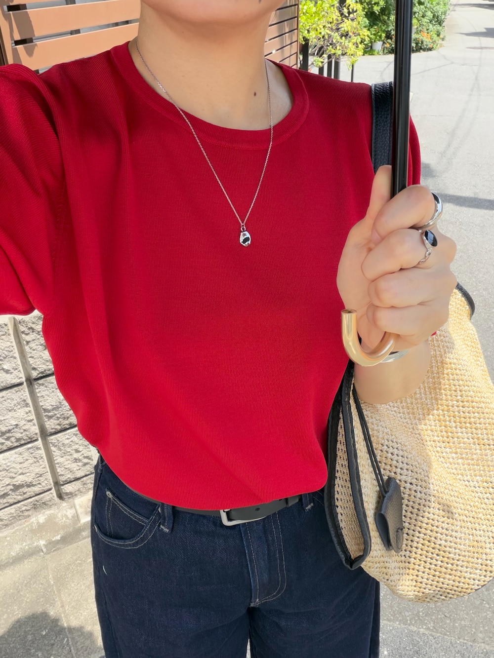 ブラック系のショルダーバッグ、レッド系のTシャツ/カットソー、ブルー系のデニムパンツを着用したレディースの夏コーディネートの5枚目の写真