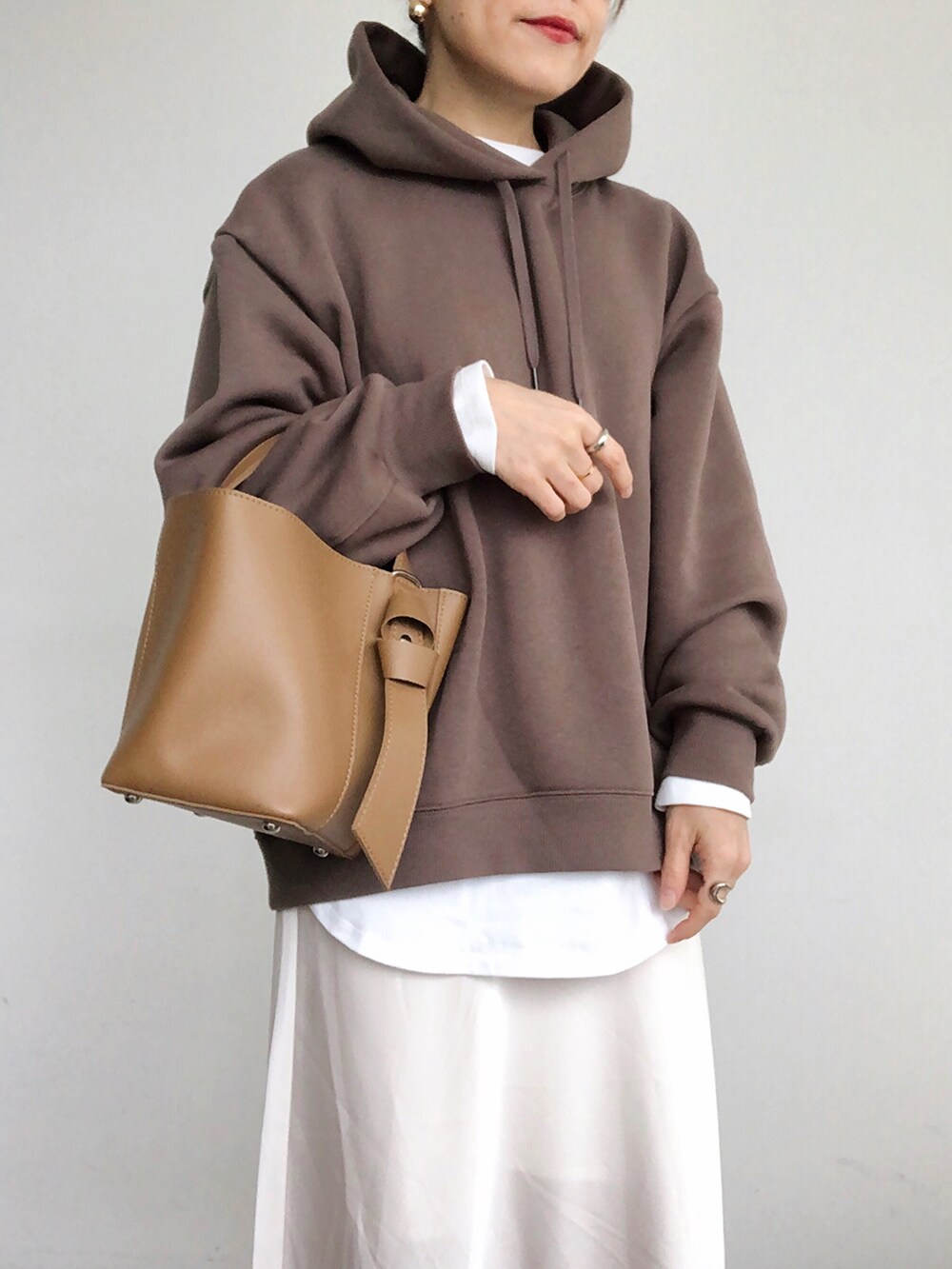 ブラウン系のパーカー、ホワイト系のスカート、ブラウン系のショルダーバッグを着用したレディースの秋コーディネートの3枚目の写真