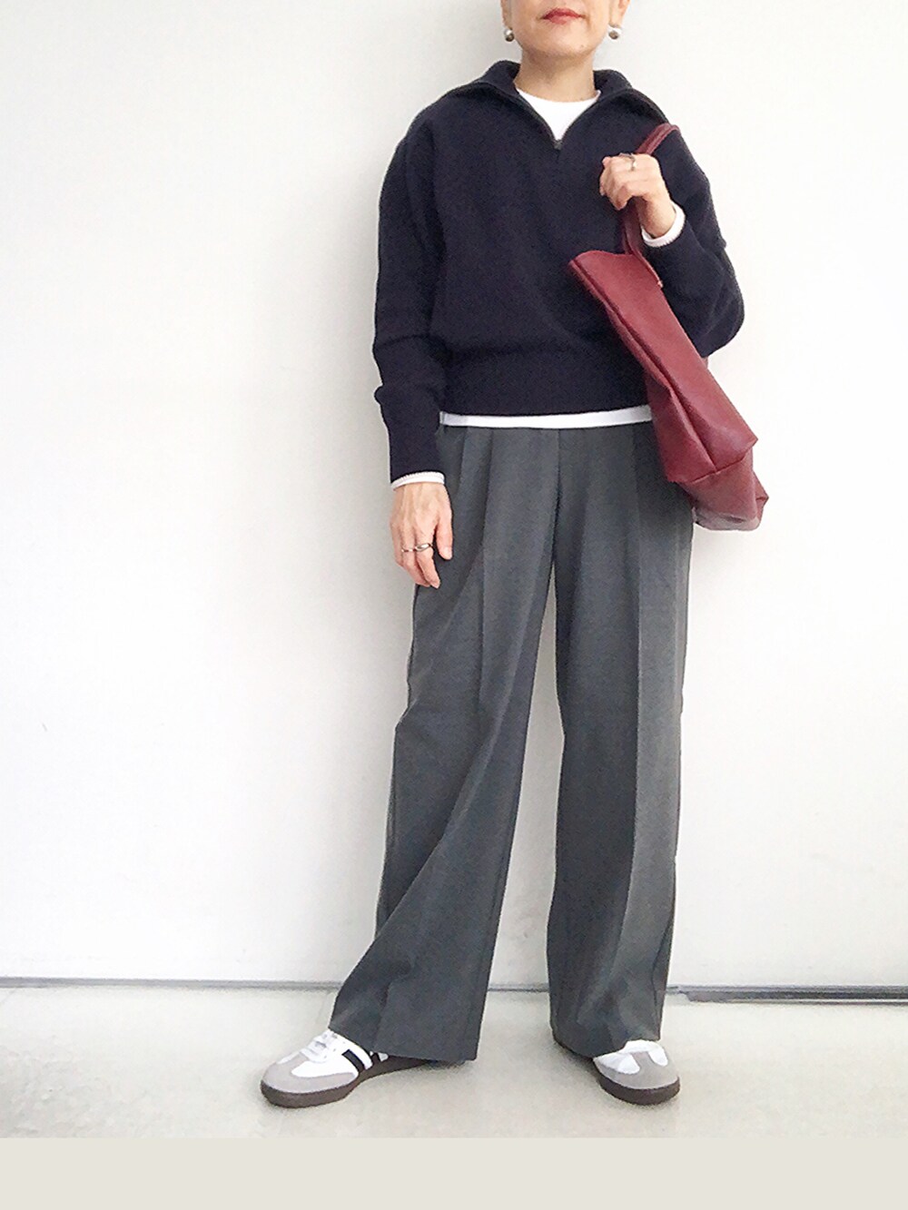 ブルー系のニット/セーター、グレー系のスラックス、レッド系のバックパック/リュックを着用したレディースの秋コーディネートの2枚目の写真