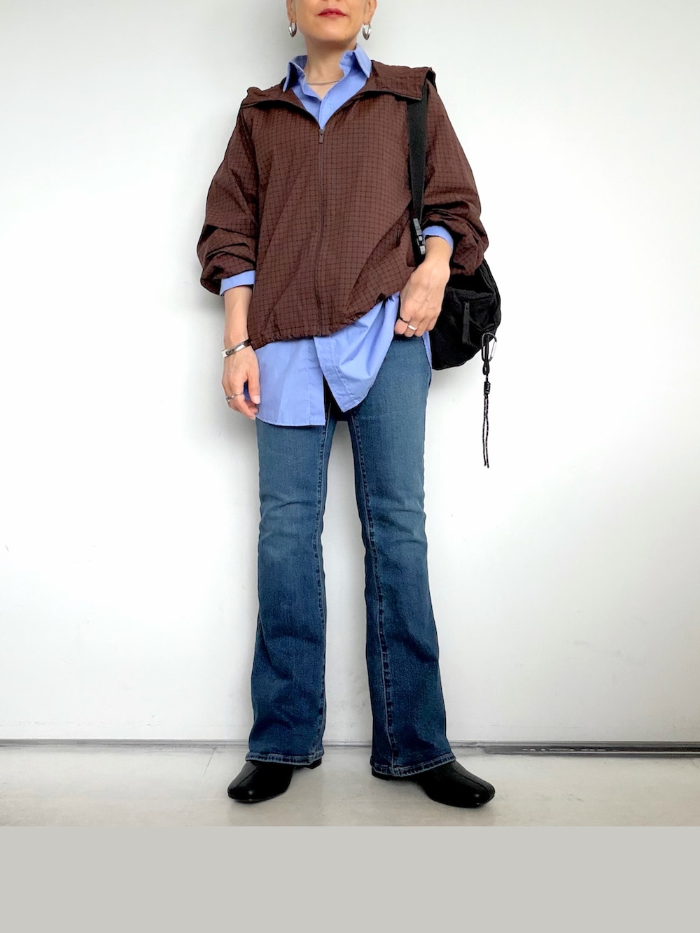 ブラック系のボディバッグ/ウエストポーチ、ブルー系のシャツ/ブラウス、ブラウン系のその他アウターを着用したレディースの秋コーディネートの3枚目の写真