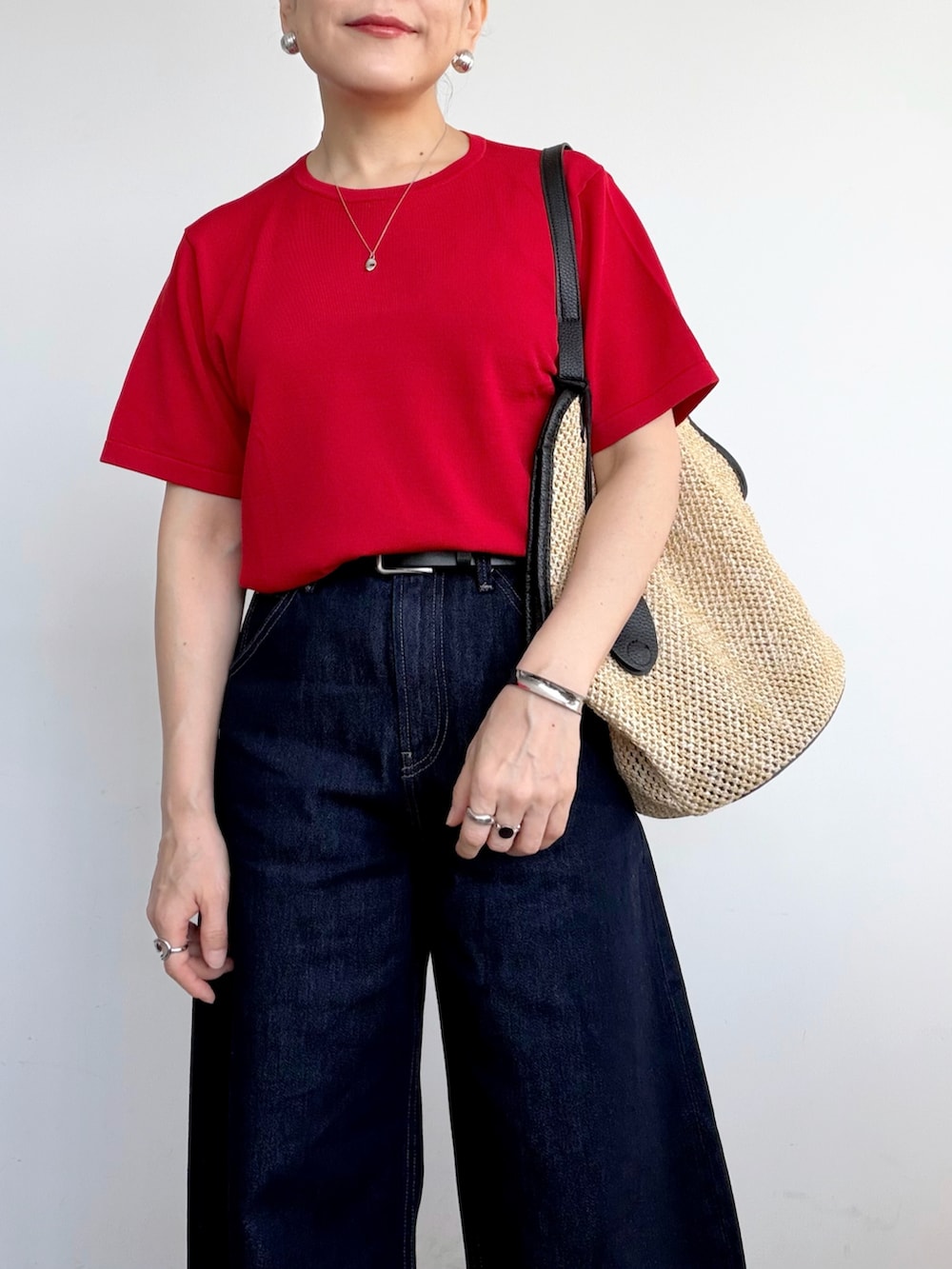 ブラック系のショルダーバッグ、レッド系のTシャツ/カットソー、ブルー系のデニムパンツを着用したレディースの夏コーディネートの3枚目の写真