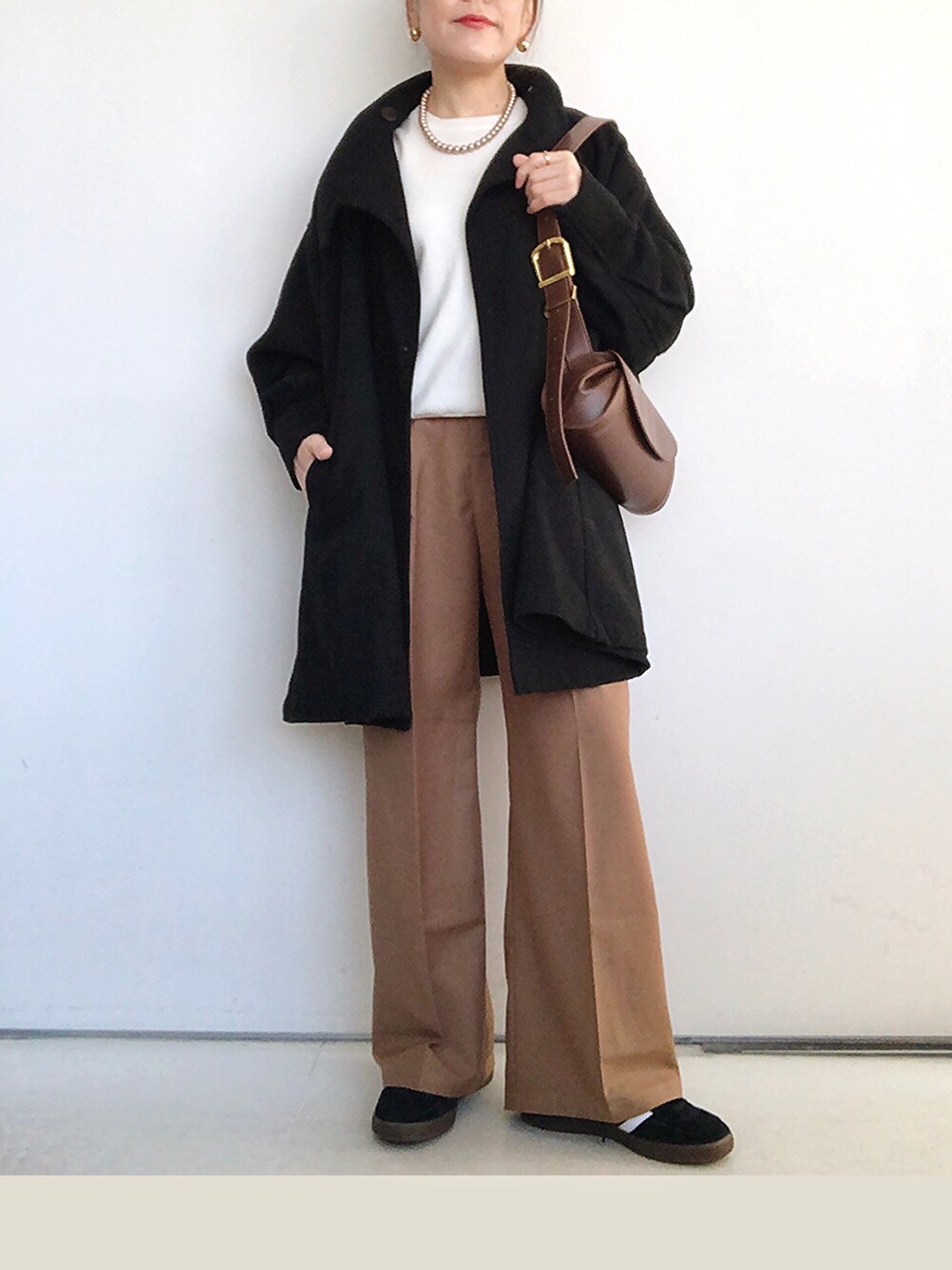 ブラック系のその他アウター、ホワイト系のニット/セーター、ブラウン系のその他パンツを着用したレディースの冬コーディネートの3枚目の写真