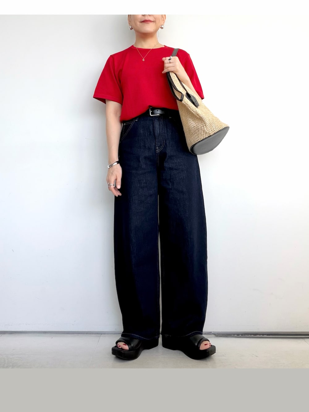 ブラック系のショルダーバッグ、レッド系のTシャツ/カットソー、ブルー系のデニムパンツを着用したレディースの夏コーディネートの2枚目の写真