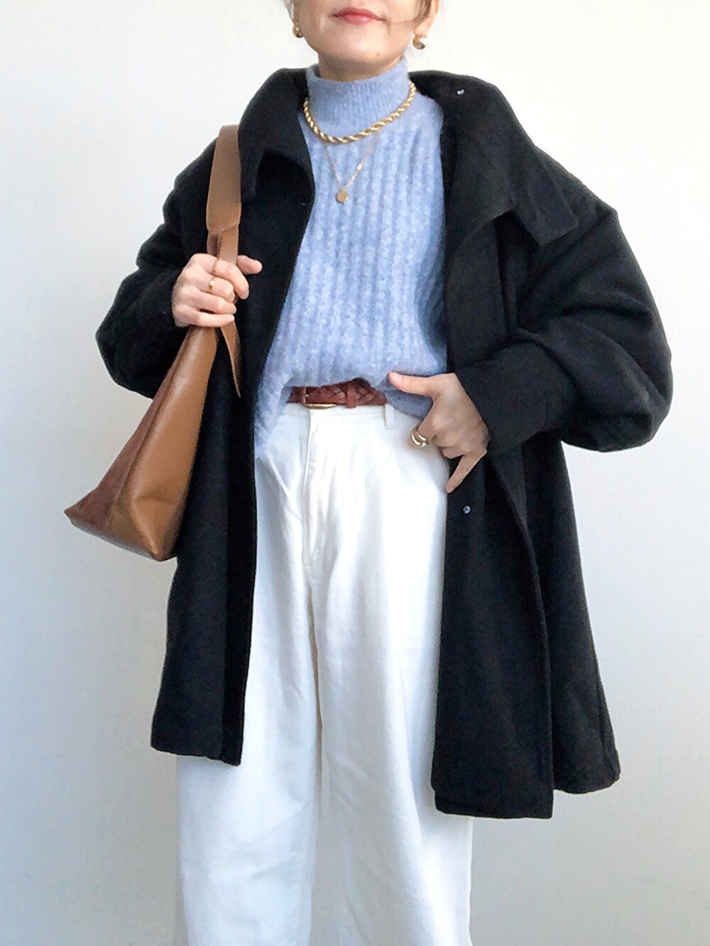 ブラック系のその他アウター、ブルー系のニット/セーター、ホワイト系のデニムパンツを着用したレディースの冬コーディネートの3枚目の写真