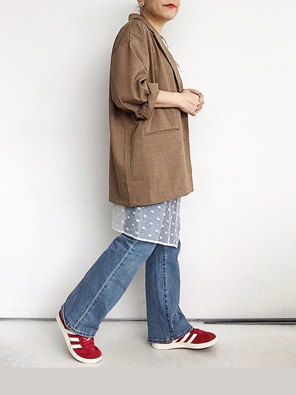 ホワイト系のスカート、ベージュ系のテーラードジャケット、レッド系のスニーカーを着用したレディースの夏コーディネートの2枚目の写真