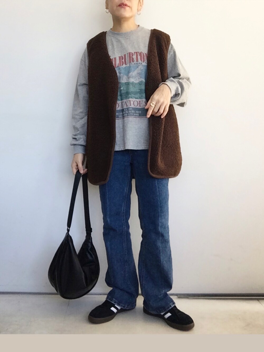 ブラウン系のベスト、グレー系のTシャツ/カットソー、ブルー系のデニムパンツを着用したレディースの秋コーディネートの3枚目の写真