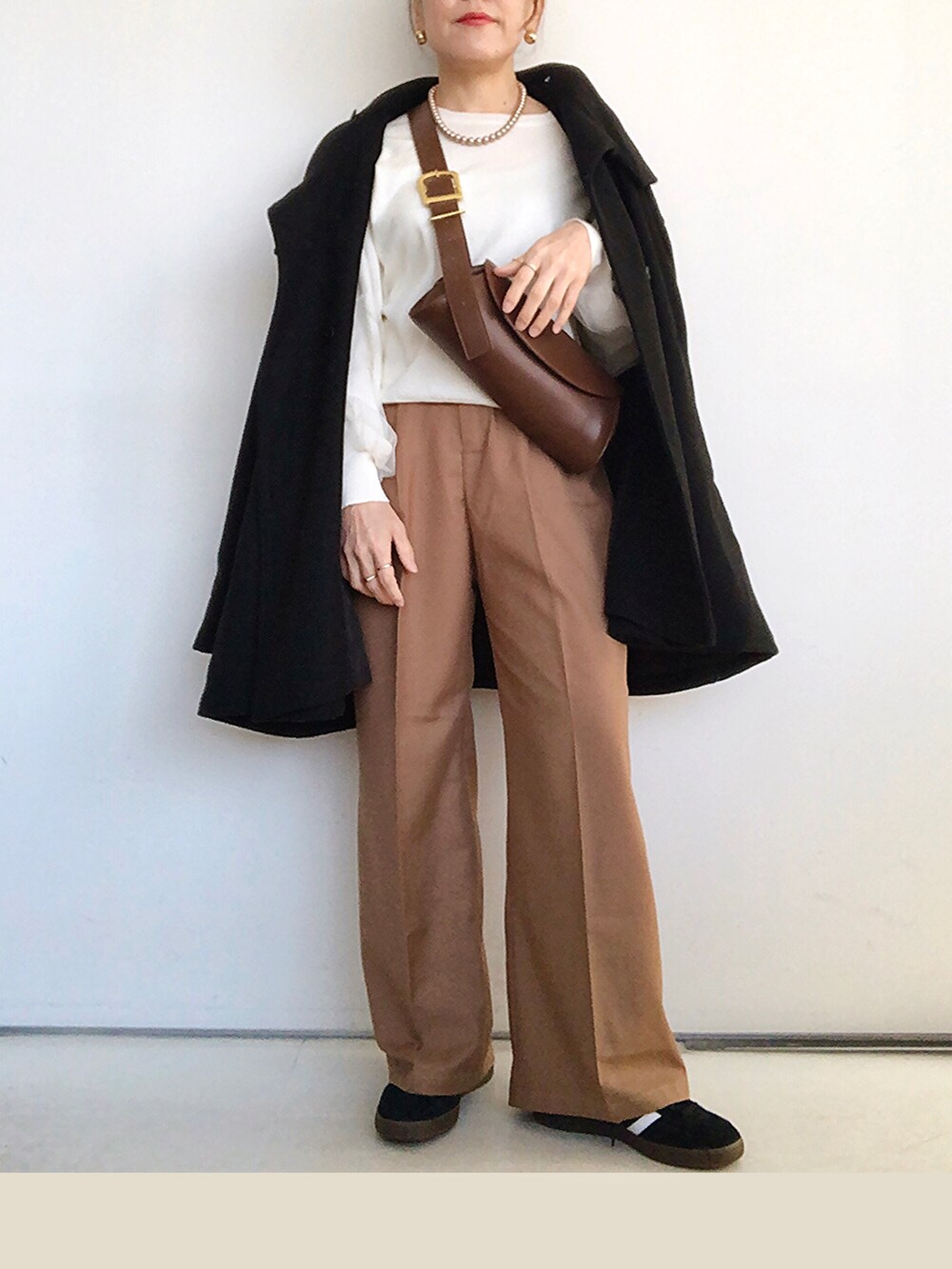 ブラック系のその他アウター、ホワイト系のニット/セーター、ブラウン系のその他パンツを着用したレディースの冬コーディネートの4枚目の写真