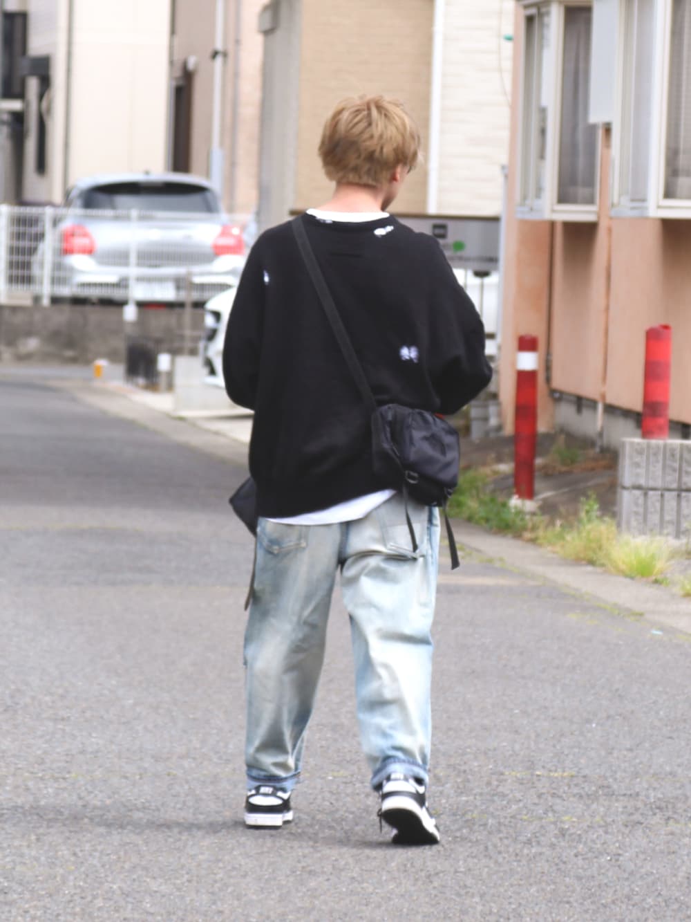 ブルー系のデニムパンツ、ブラック系のニット/セーター、ブラック系のショルダーバッグを着用したメンズの春コーディネートの2枚目の写真