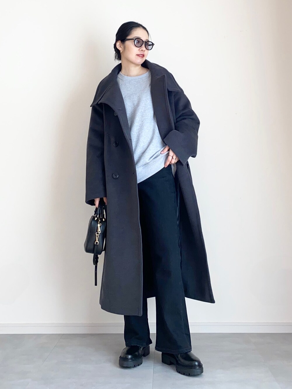 グレー系のステンカラーコート、グレー系のスウェット、ブラック系のデニムパンツを着用したレディースの冬コーディネートの2枚目の写真