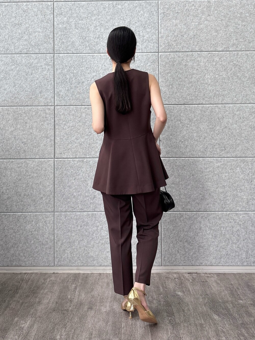 ブラック系のハンドバッグ、ブラウン系のベスト、ブラウン系のその他パンツを着用したレディースの秋コーディネートの4枚目の写真