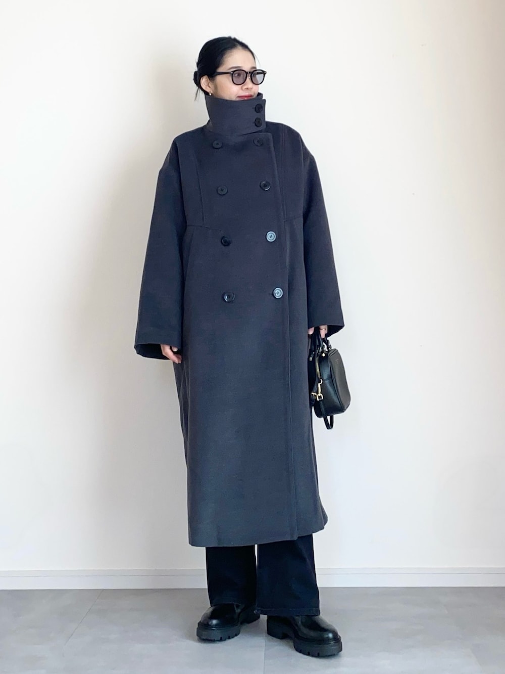 グレー系のステンカラーコート、グレー系のスウェット、ブラック系のデニムパンツを着用したレディースの冬コーディネートの3枚目の写真