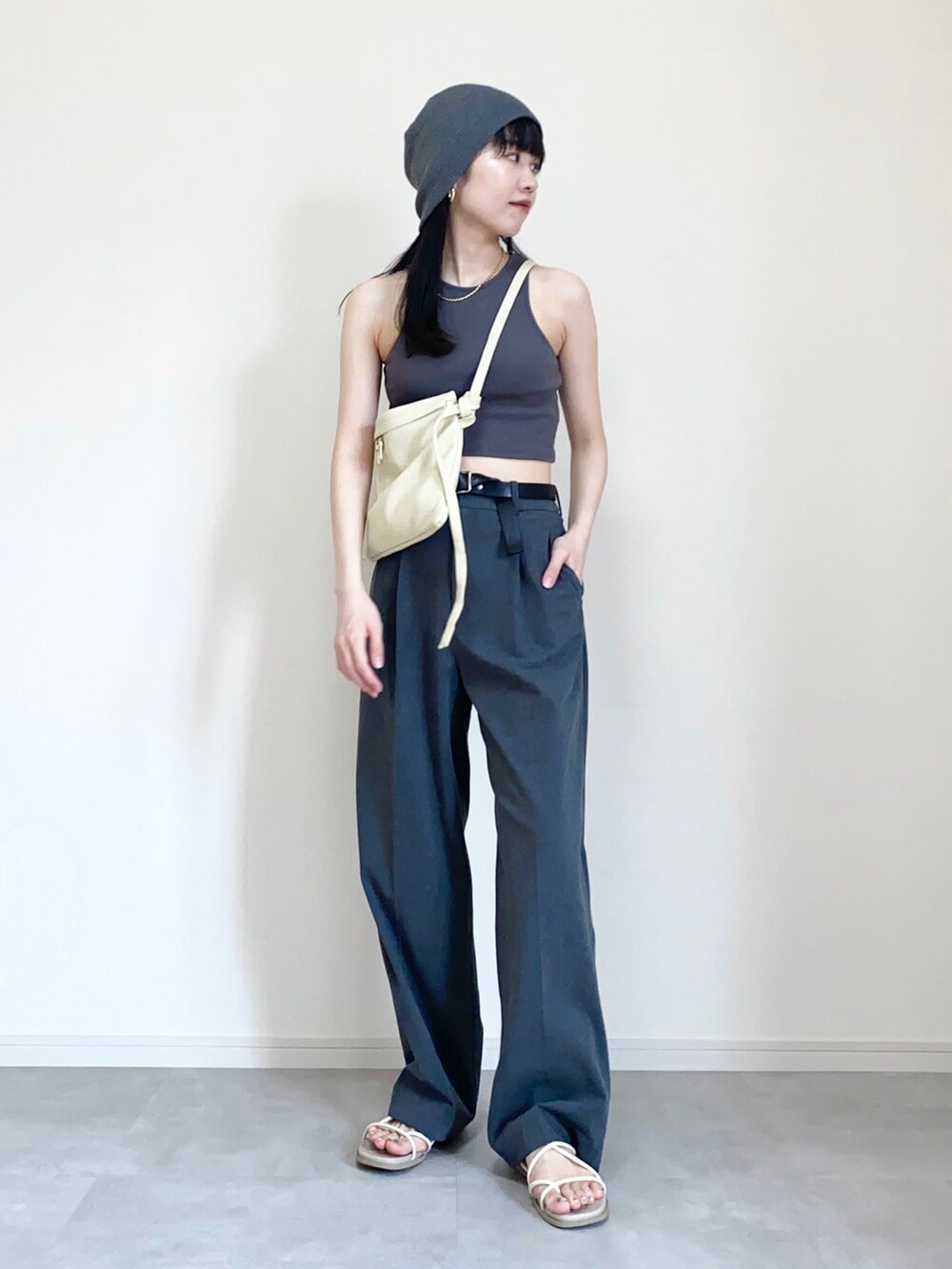 グレー系のタンクトップ、グレー系のスラックス、ホワイト系のショルダーバッグを着用したレディースの夏コーディネートの2枚目の写真