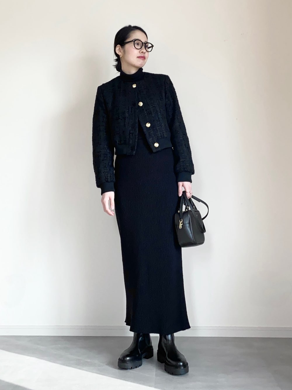 ブラック系のノーカラージャケット、ブラック系のスカート、ブラック系のブーツを着用したレディースの冬コーディネートの2枚目の写真