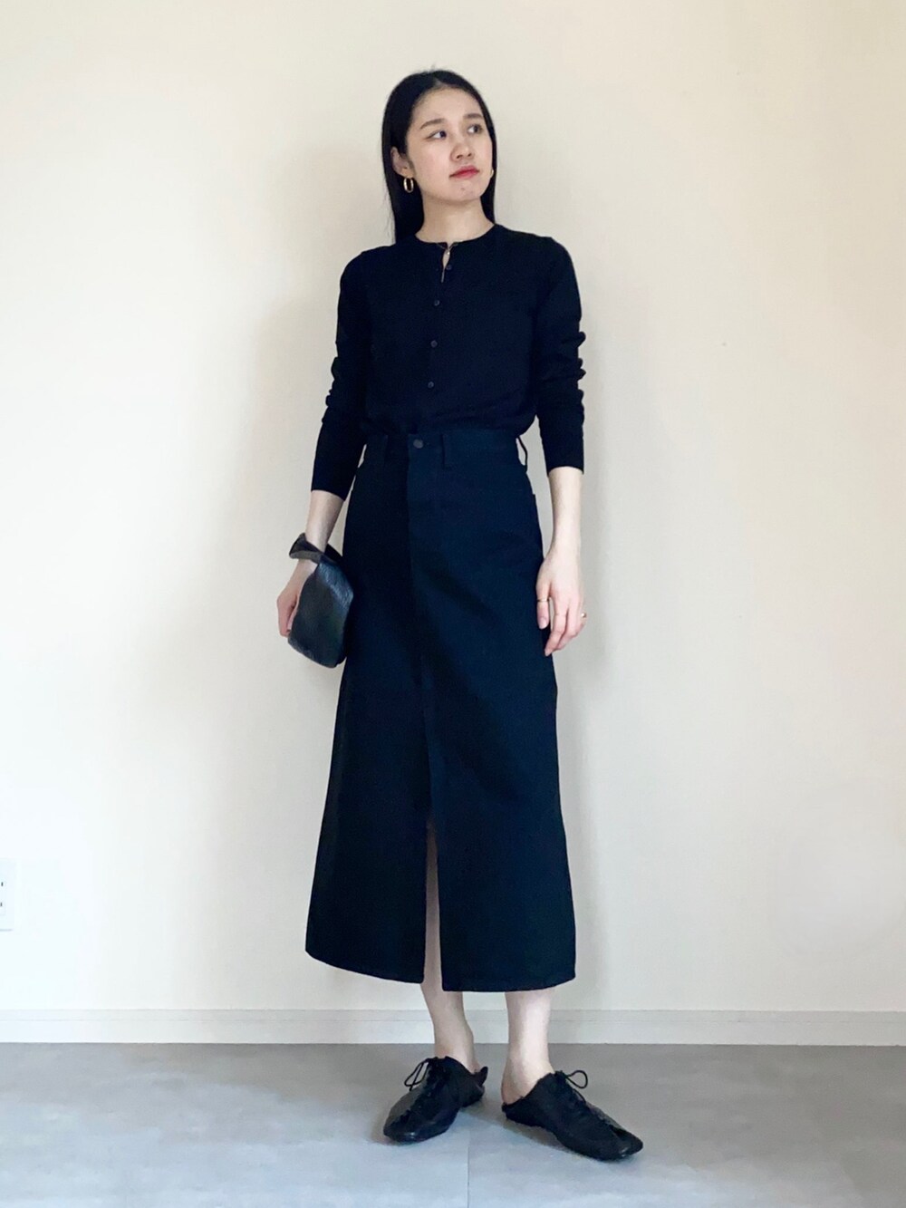 ブラック系のスリッポン、ブラック系のハンドバッグ、ブラック系のデニムスカートを着用したレディースの春コーディネートの2枚目の写真