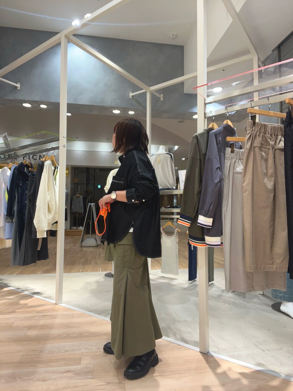 ブラック系のシャツ/ブラウス、グリーン系のスカート、オレンジ系のカードケースを着用したレディースの秋コーディネートの2枚目の写真