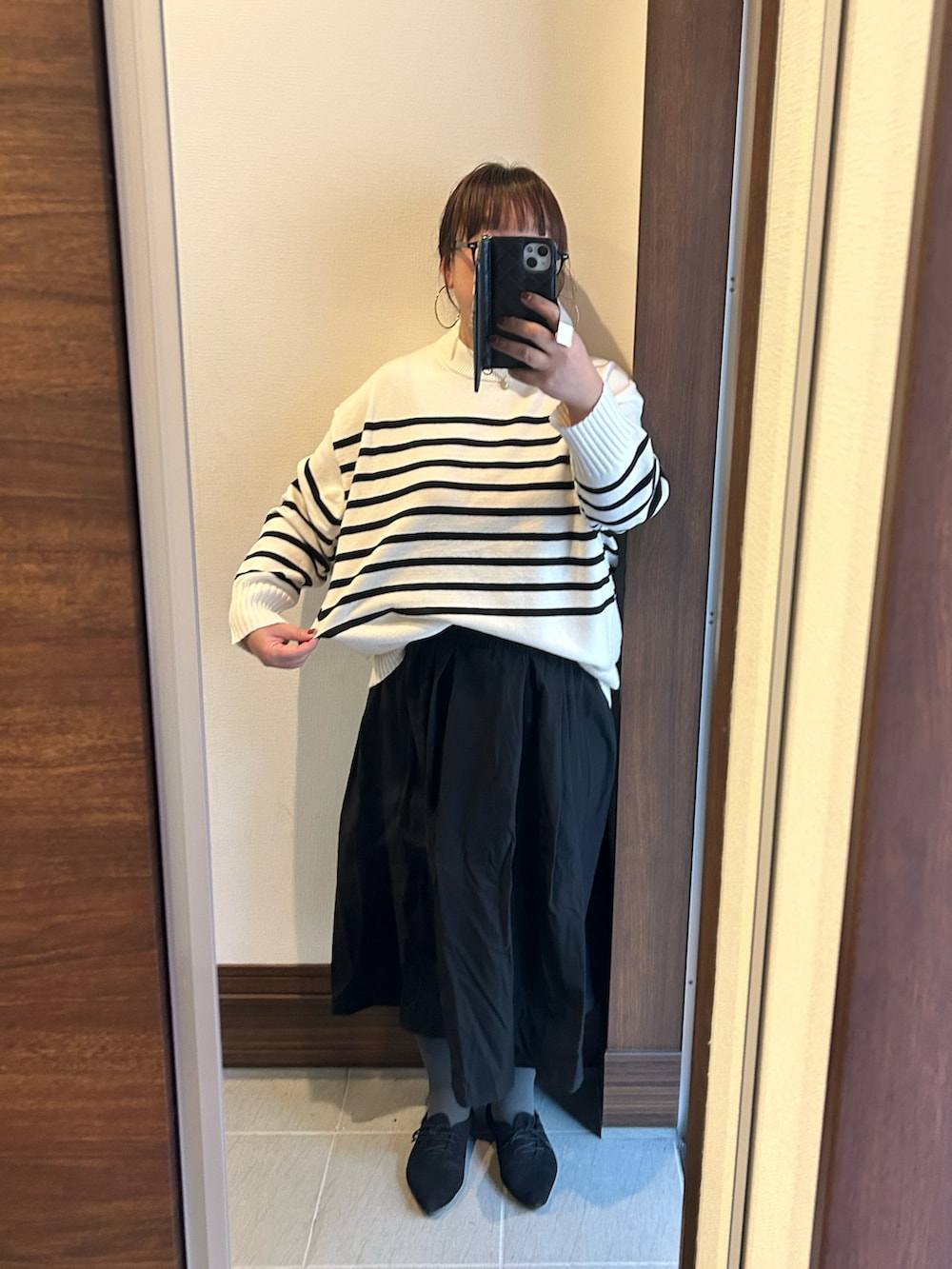 ホワイト系のニット/セーター、ブラック系のスカート、ブラック系のショルダーバッグを着用したレディースの冬コーディネートの2枚目の写真