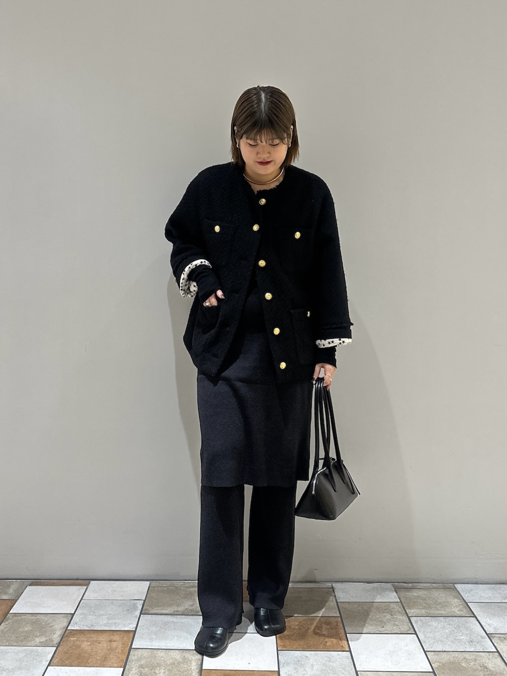 ブラック系のノーカラージャケット、ブラック系のTシャツ/カットソー、ブラック系のボストンバッグを着用したレディースの秋コーディネートの3枚目の写真