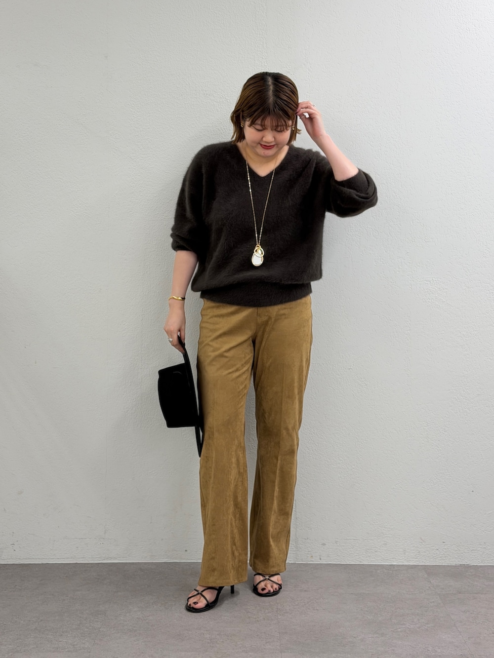 ブラウン系のニット/セーター、イエロー系のその他パンツ、ブラック系のサンダルを着用したレディースの秋コーディネートの2枚目の写真