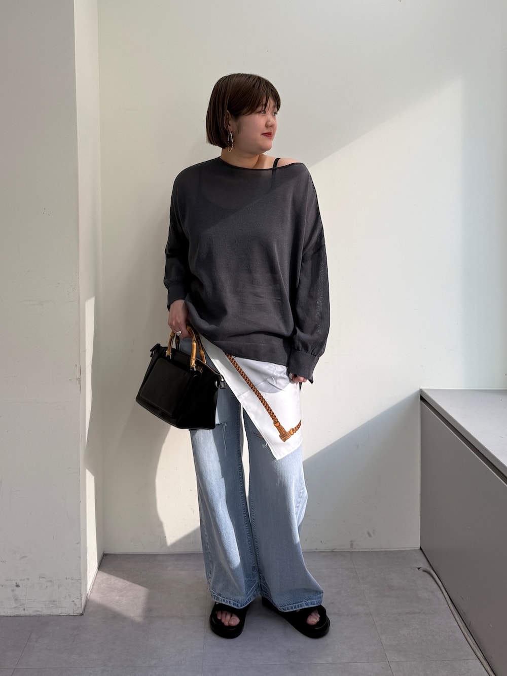 グレー系のニット/セーター、ブルー系のデニムパンツ、ブラック系のサンダルを着用したレディースの春コーディネートの2枚目の写真