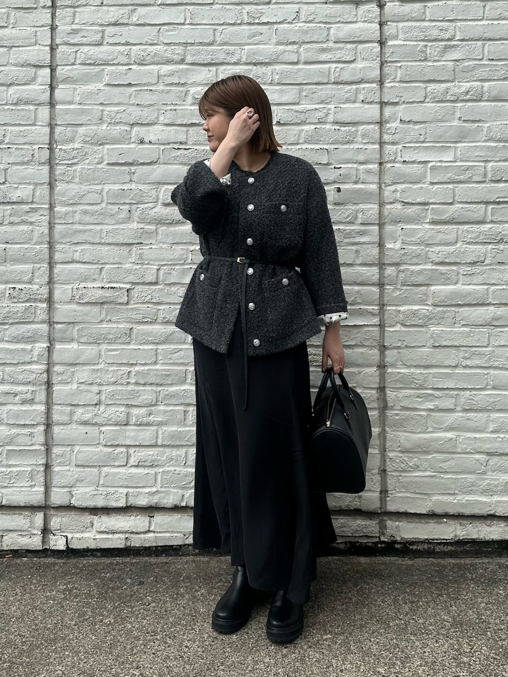 グレー系のノーカラージャケット、ブラック系のワンピース、ブラック系のブーツを着用したレディースの秋コーディネートの2枚目の写真