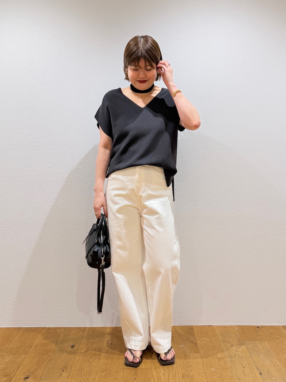 グレー系のニット/セーター、ブラック系のボストンバッグ、ホワイト系のデニムパンツを着用したレディースの夏コーディネートの2枚目の写真