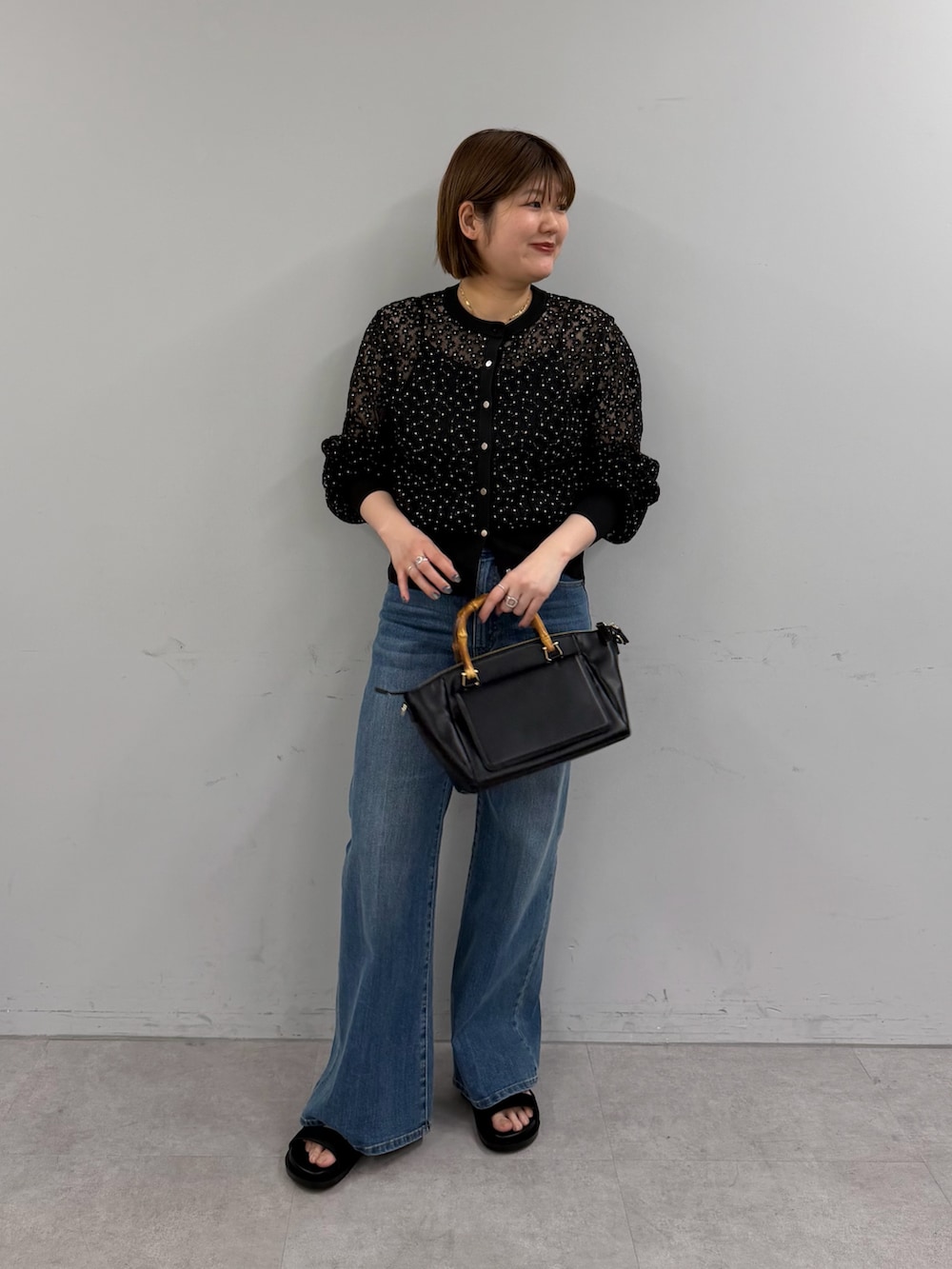 ブラック系のカーディガン/ボレロ、ブルー系のデニムパンツ、ブラック系のトートバッグを着用したレディースの春コーディネートの3枚目の写真