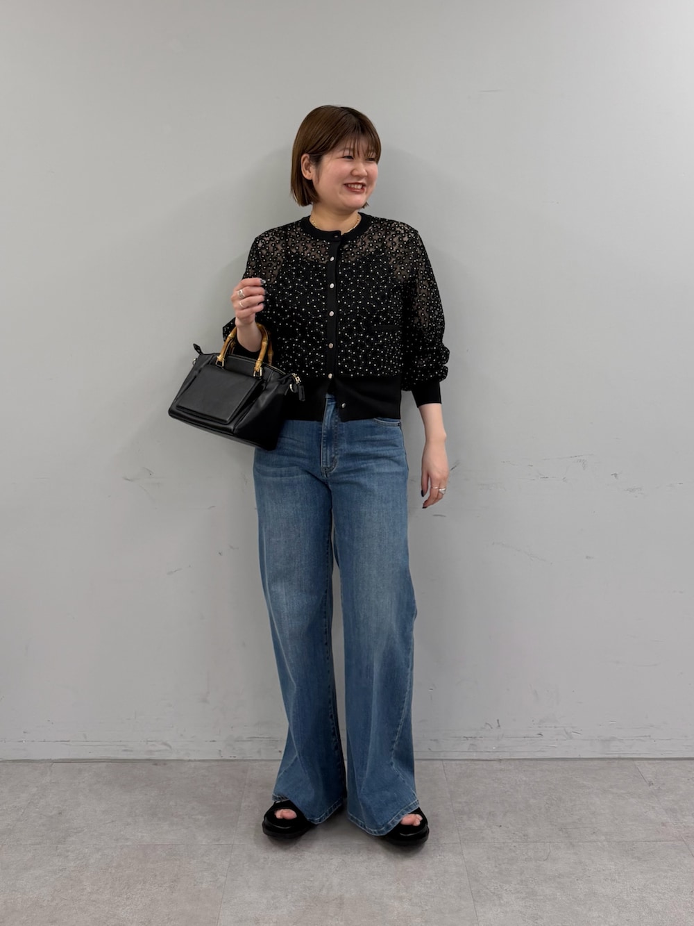 ブラック系のカーディガン/ボレロ、ブルー系のデニムパンツ、ブラック系のトートバッグを着用したレディースの春コーディネートの2枚目の写真