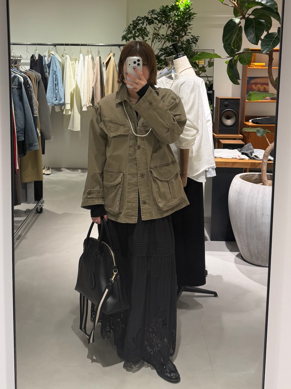 グリーン系のその他アウター、ブラック系のスカート、ブラック系のボストンバッグを着用したレディースの春コーディネートの2枚目の写真
