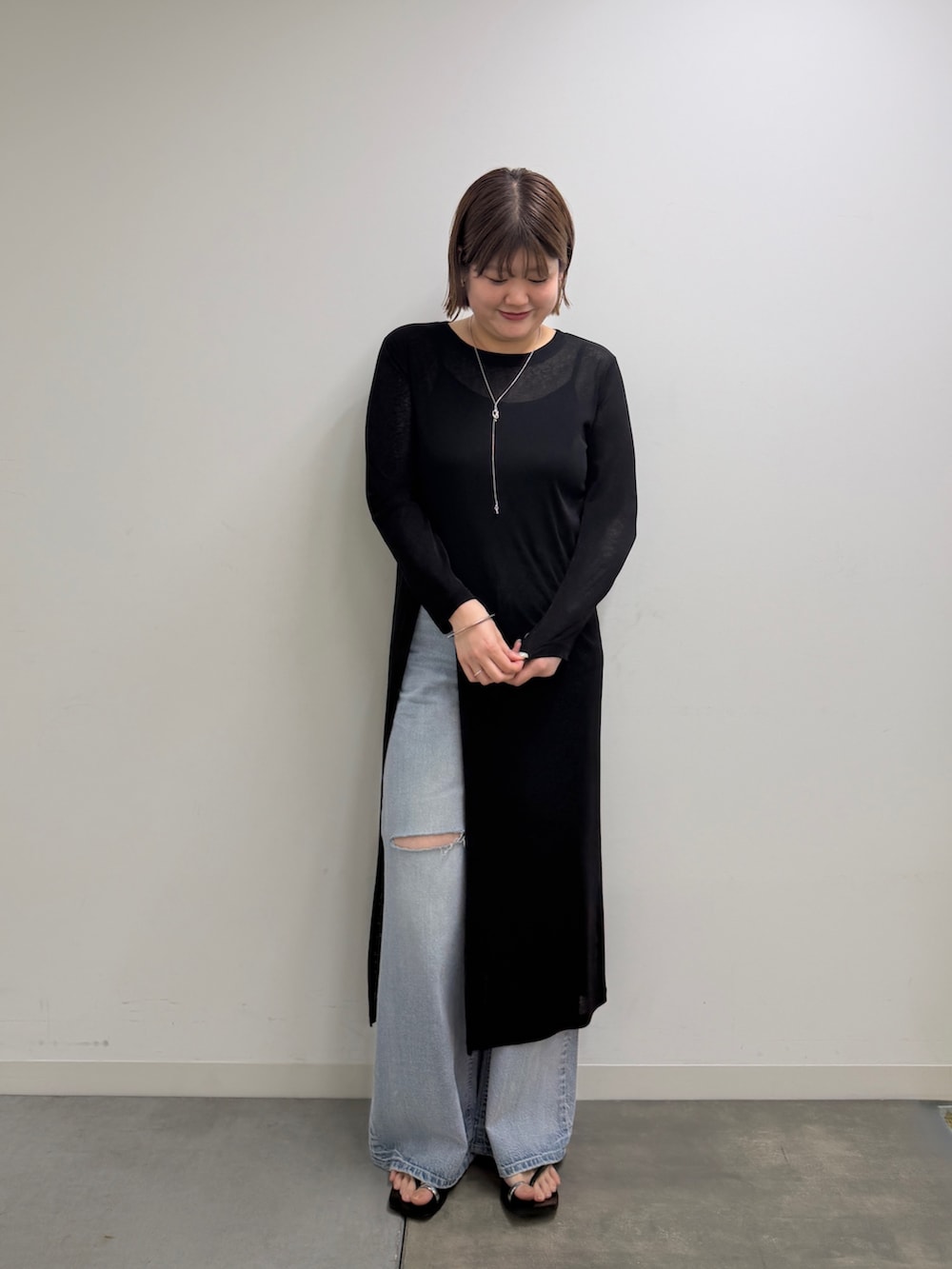 ブルー系のデニムパンツ、シルバー系のサンダル、ブラック系のワンピースを着用したレディースの春コーディネートの2枚目の写真
