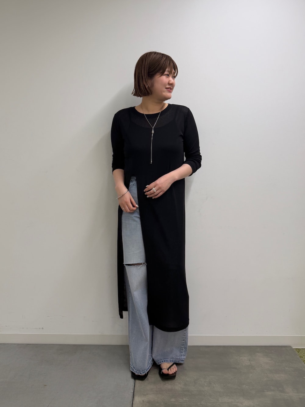 ブルー系のデニムパンツ、シルバー系のサンダル、ブラック系のワンピースを着用したレディースの春コーディネートの3枚目の写真