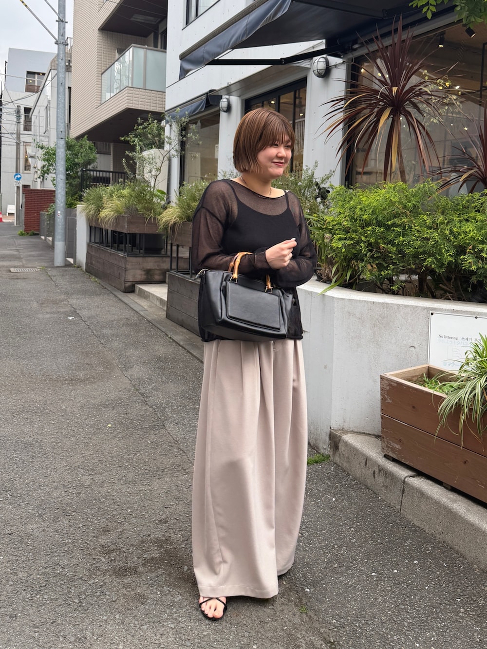 ブラック系のハンドバッグ、ベージュ系のその他パンツ、ブラック系のサンダルを着用したレディースの春コーディネートの2枚目の写真