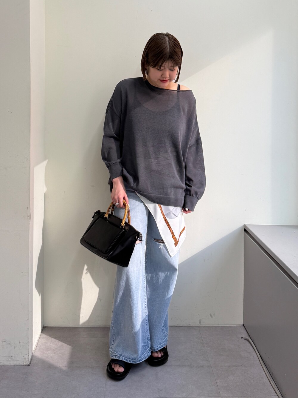グレー系のニット/セーター、ブルー系のデニムパンツ、ブラック系のサンダルを着用したレディースの春コーディネートの3枚目の写真