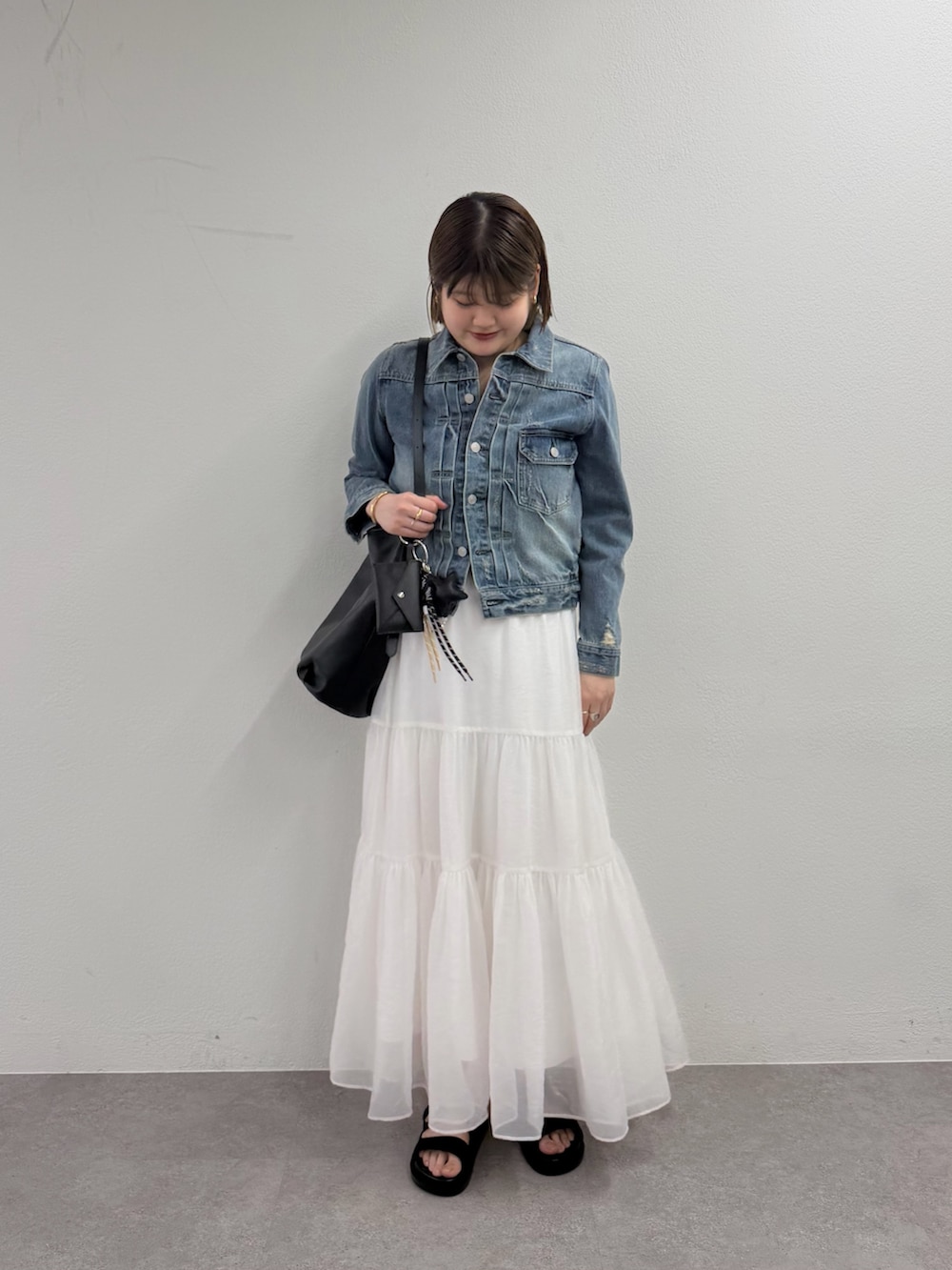 ブルー系のデニムジャケット、ブラック系のサンダル、ブラック系のトートバッグを着用したレディースの春コーディネートの2枚目の写真