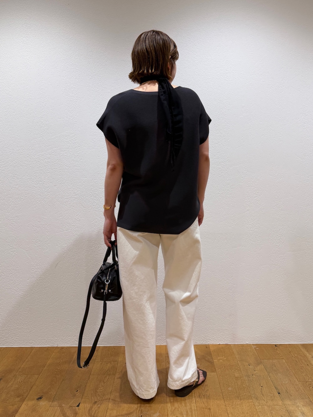 グレー系のニット/セーター、ブラック系のボストンバッグ、ホワイト系のデニムパンツを着用したレディースの夏コーディネートの3枚目の写真