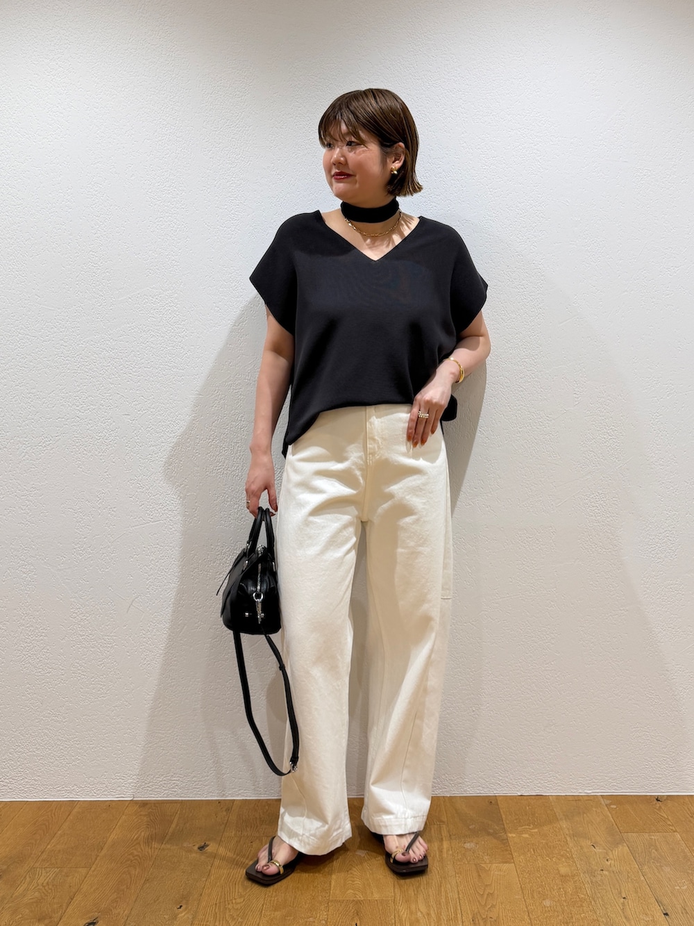 グレー系のニット/セーター、ブラック系のボストンバッグ、ホワイト系のデニムパンツを着用したレディースの夏コーディネートの4枚目の写真