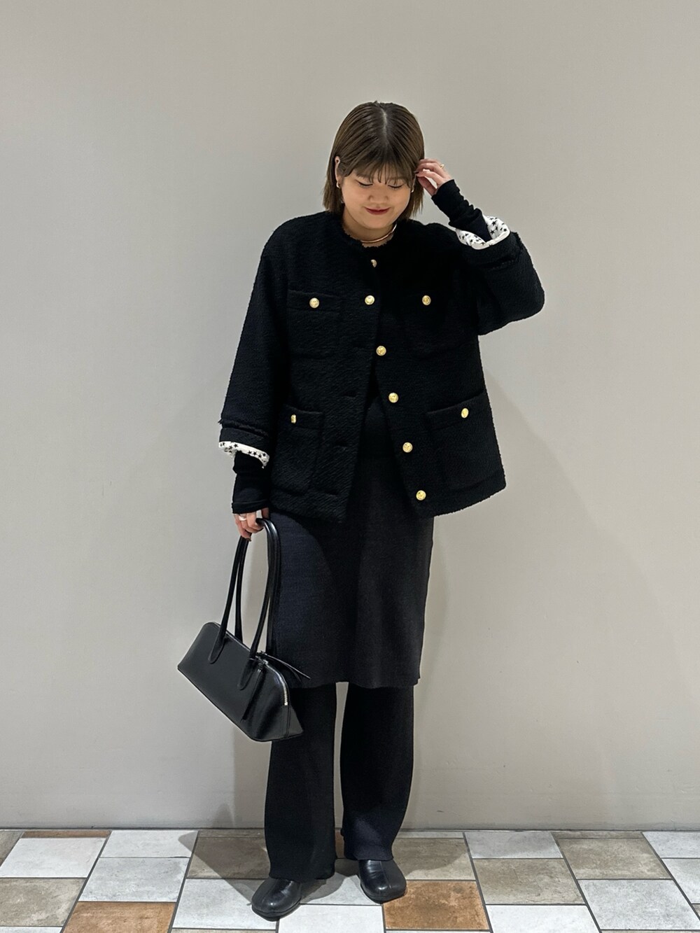 ブラック系のノーカラージャケット、ブラック系のTシャツ/カットソー、ブラック系のボストンバッグを着用したレディースの秋コーディネートの2枚目の写真