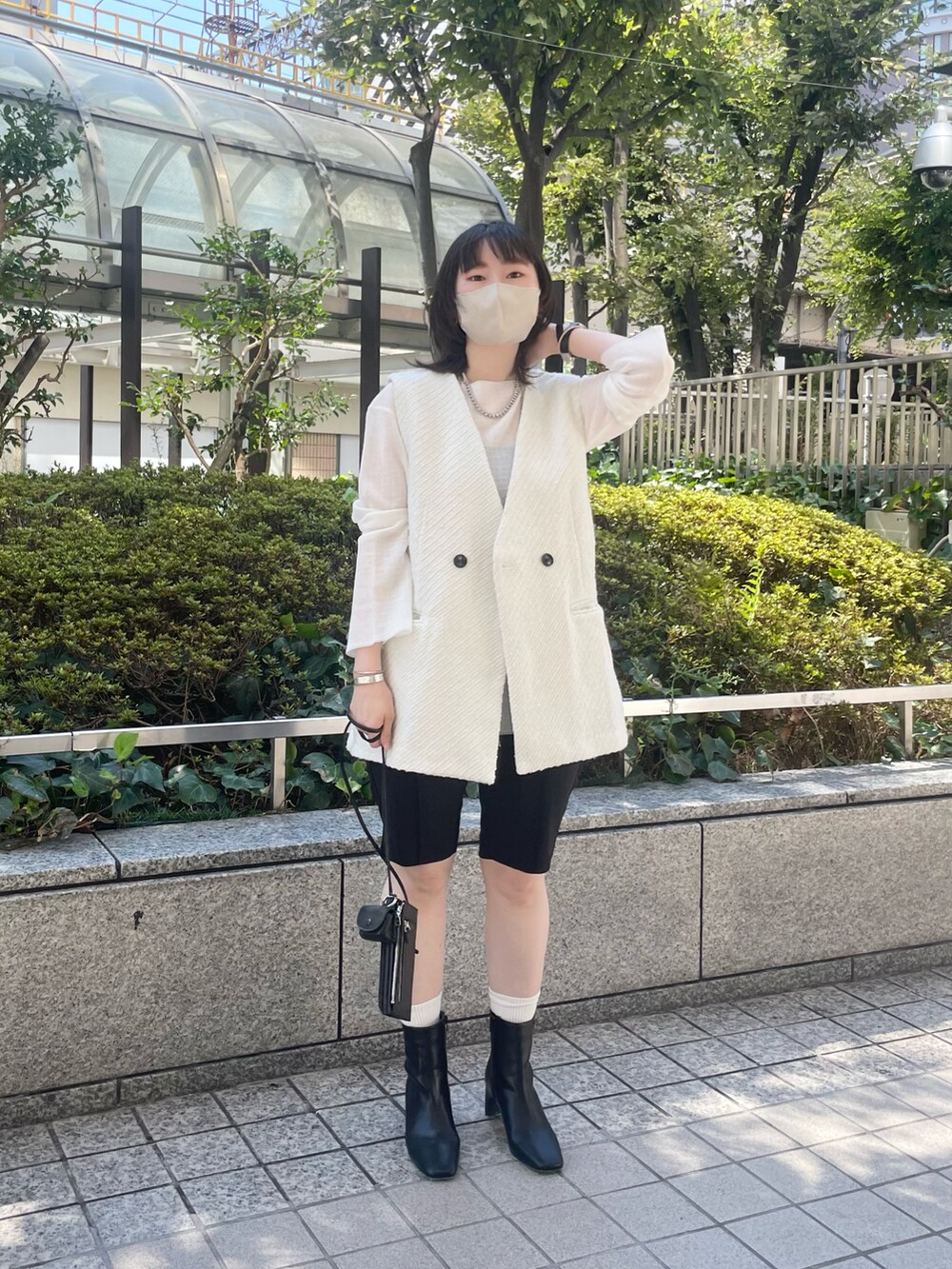 ホワイト系のベスト、ブラック系のブーツ、ブラック系のその他パンツを着用したレディースの秋コーディネートの2枚目の写真