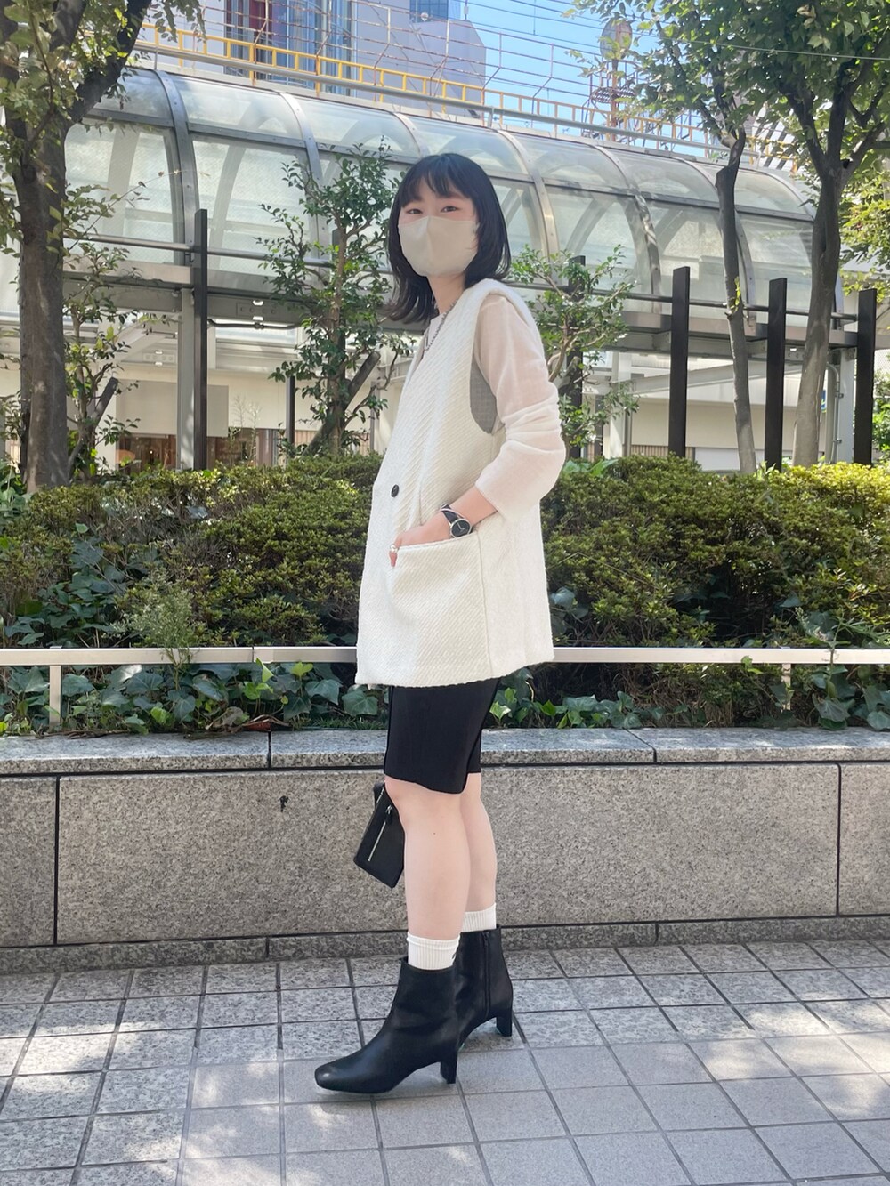 ホワイト系のベスト、ブラック系のブーツ、ブラック系のその他パンツを着用したレディースの秋コーディネートの3枚目の写真