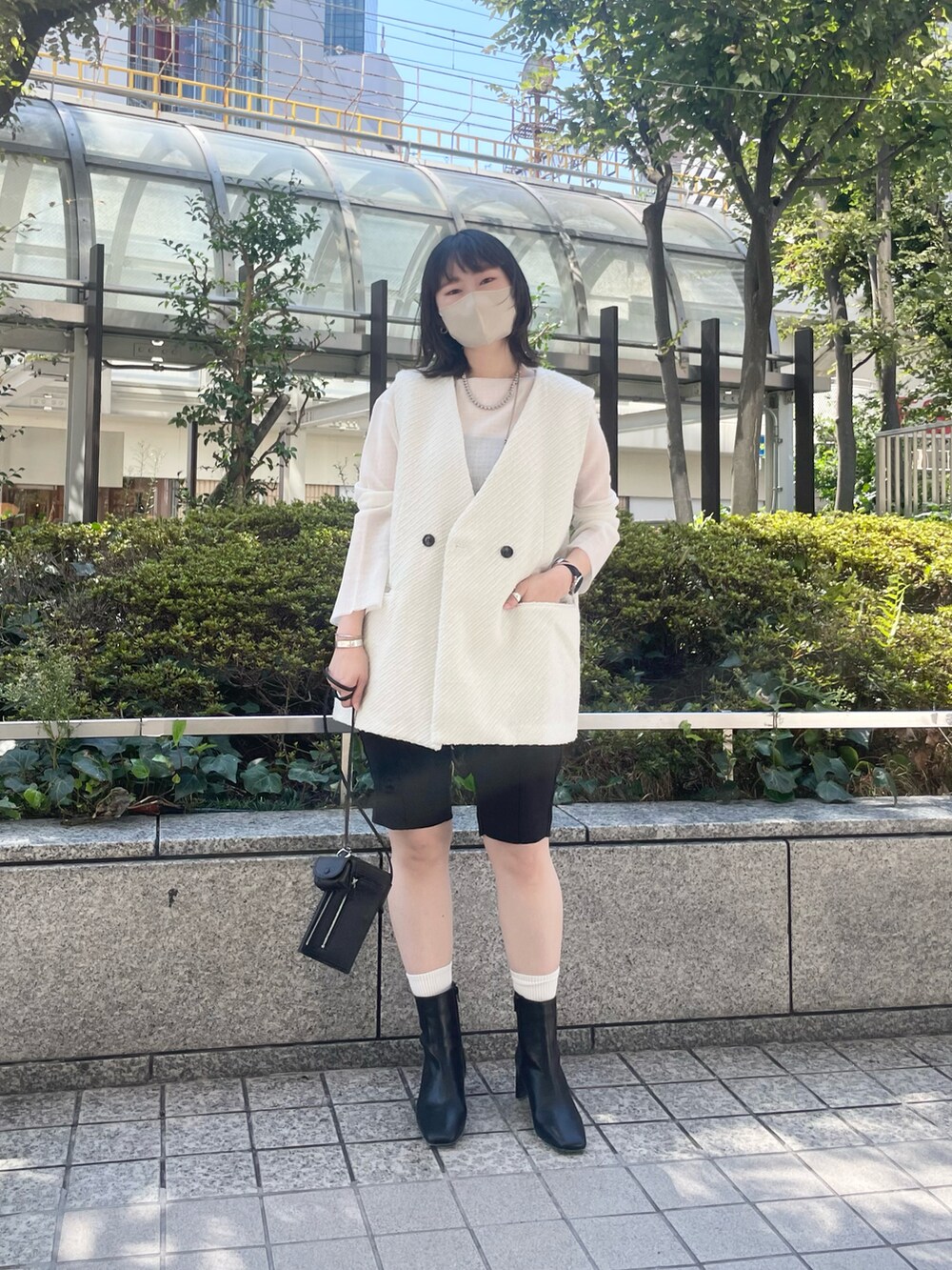 ホワイト系のベスト、ブラック系のブーツ、ブラック系のその他パンツを着用したレディースの秋コーディネートの4枚目の写真