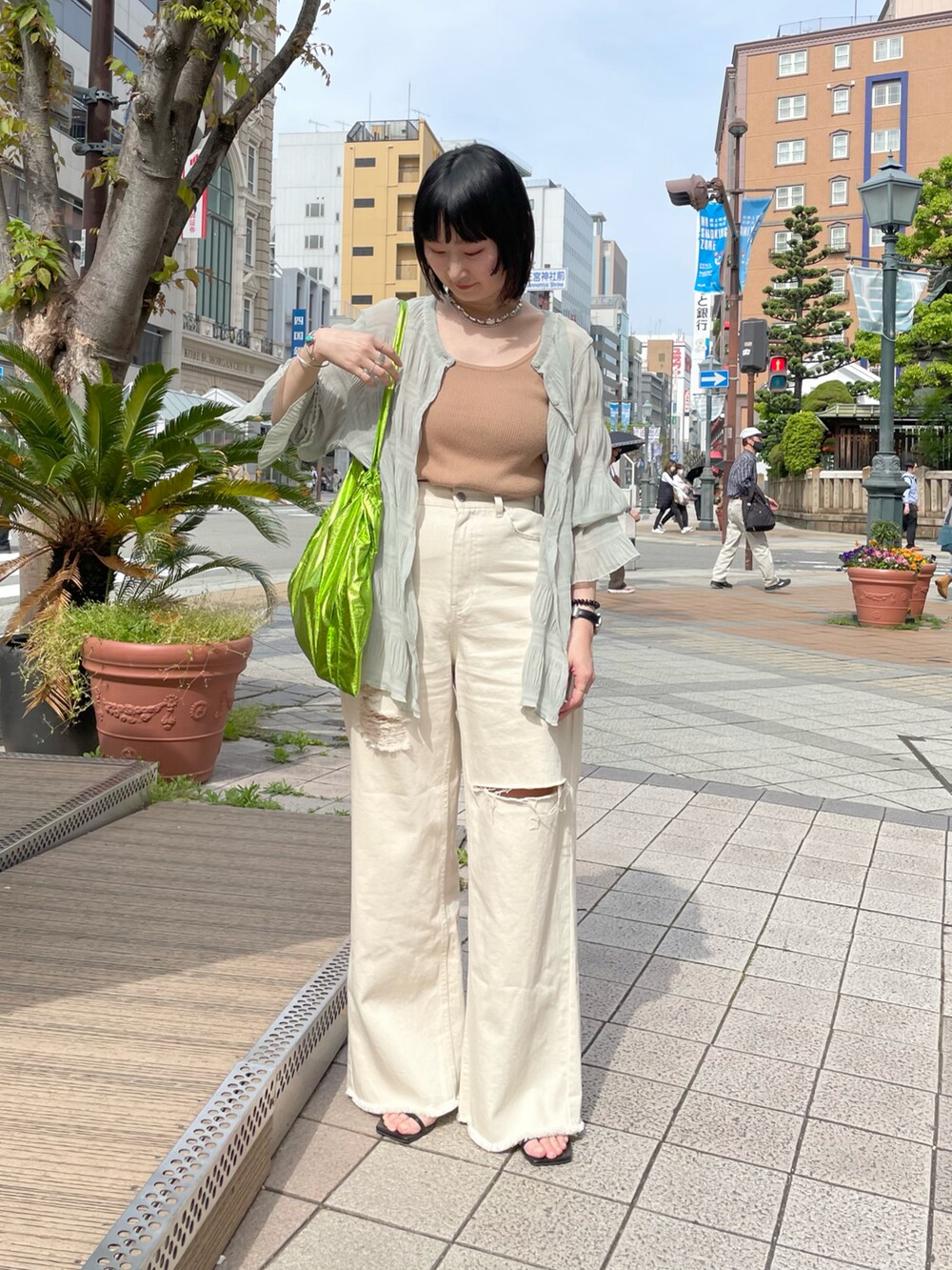 ホワイト系のデニムパンツ、ゴールド系のサンダル、ホワイト系のキャミソールを着用したレディースの春コーディネートの2枚目の写真