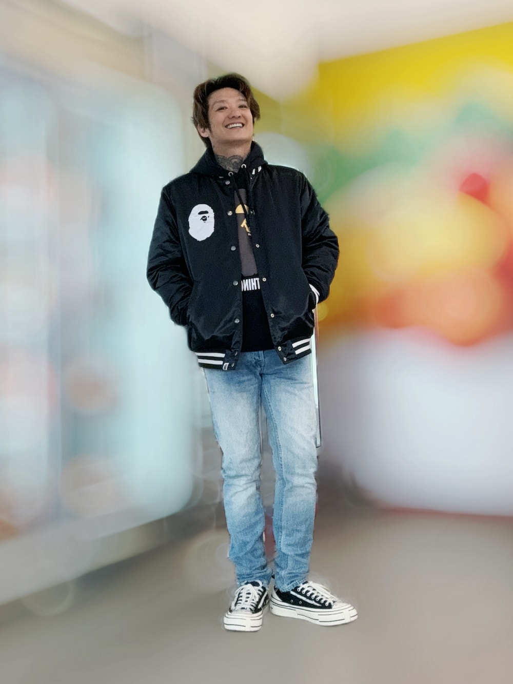 ブラック系のノーカラージャケット、その他のデニムパンツ、ブルー系のスニーカーを着用したメンズの春コーディネートの2枚目の写真