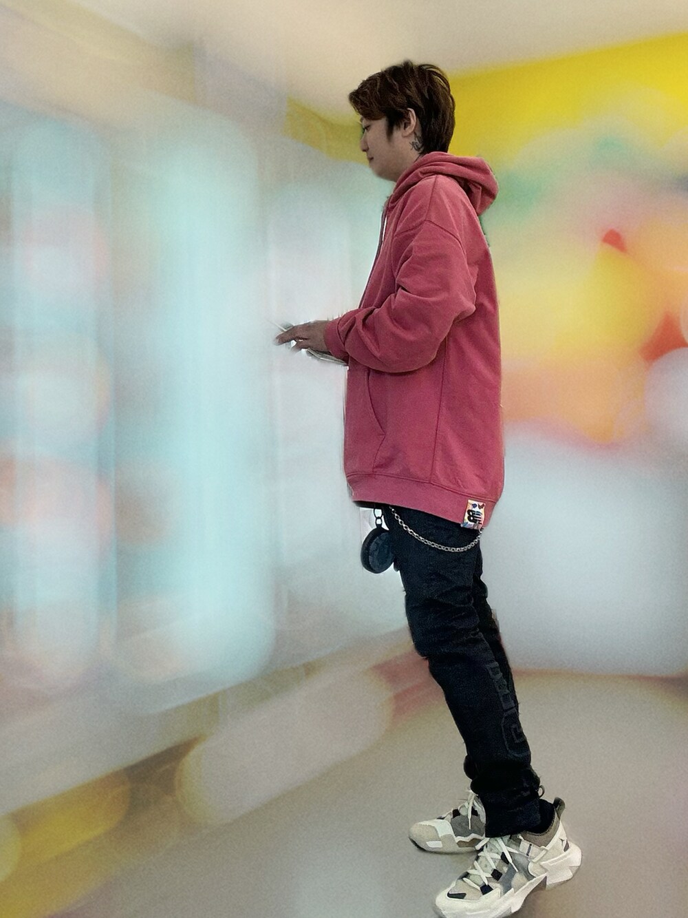 ピンク系のパーカー、ブラック系のデニムパンツ、ベージュ系のスニーカーを着用したメンズの春コーディネートの2枚目の写真