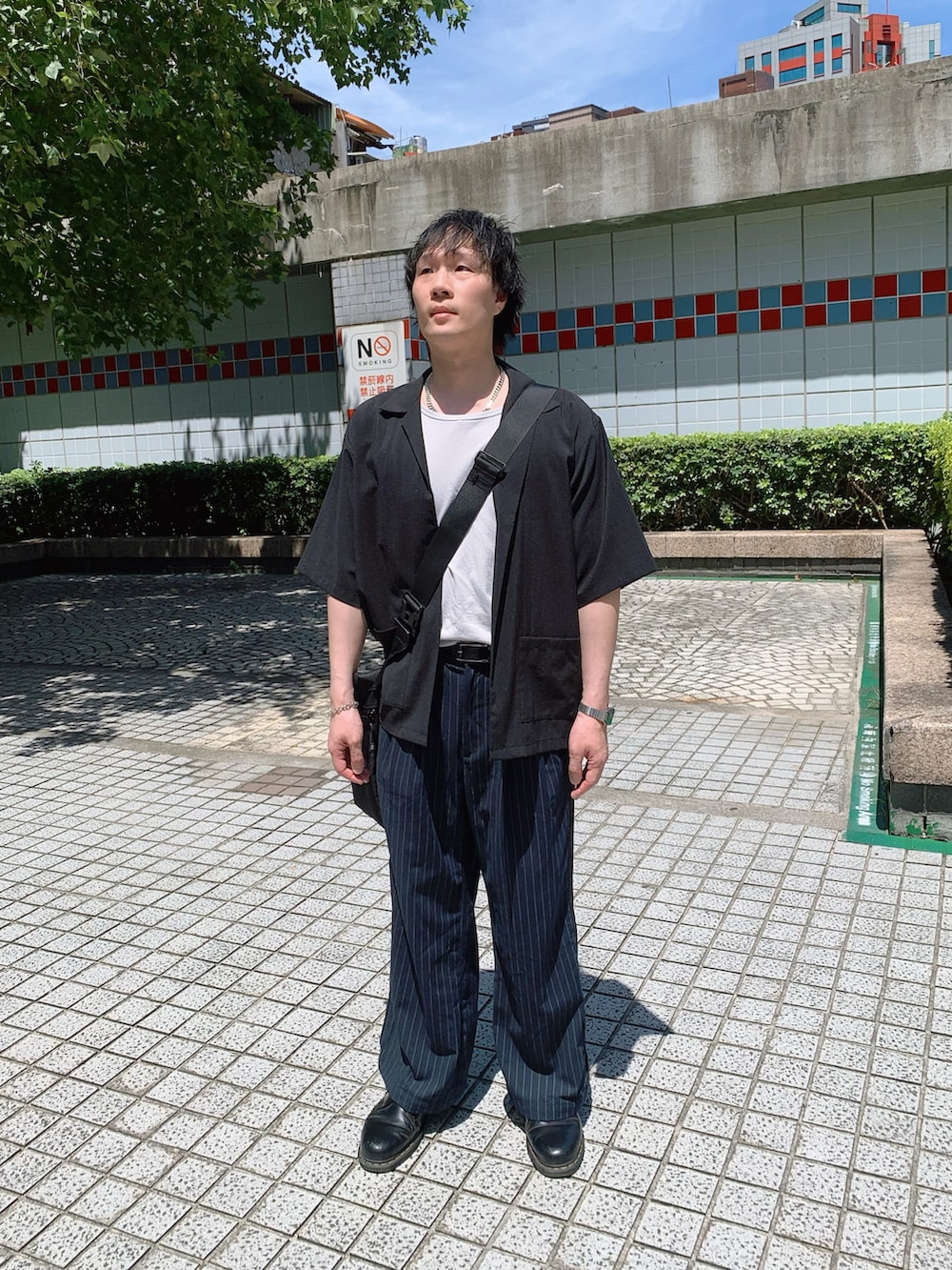 ブラック系のタンクトップ、ブラック系のショルダーバッグ、ブラック系のドレスシューズを着用したメンズの夏コーディネートの2枚目の写真