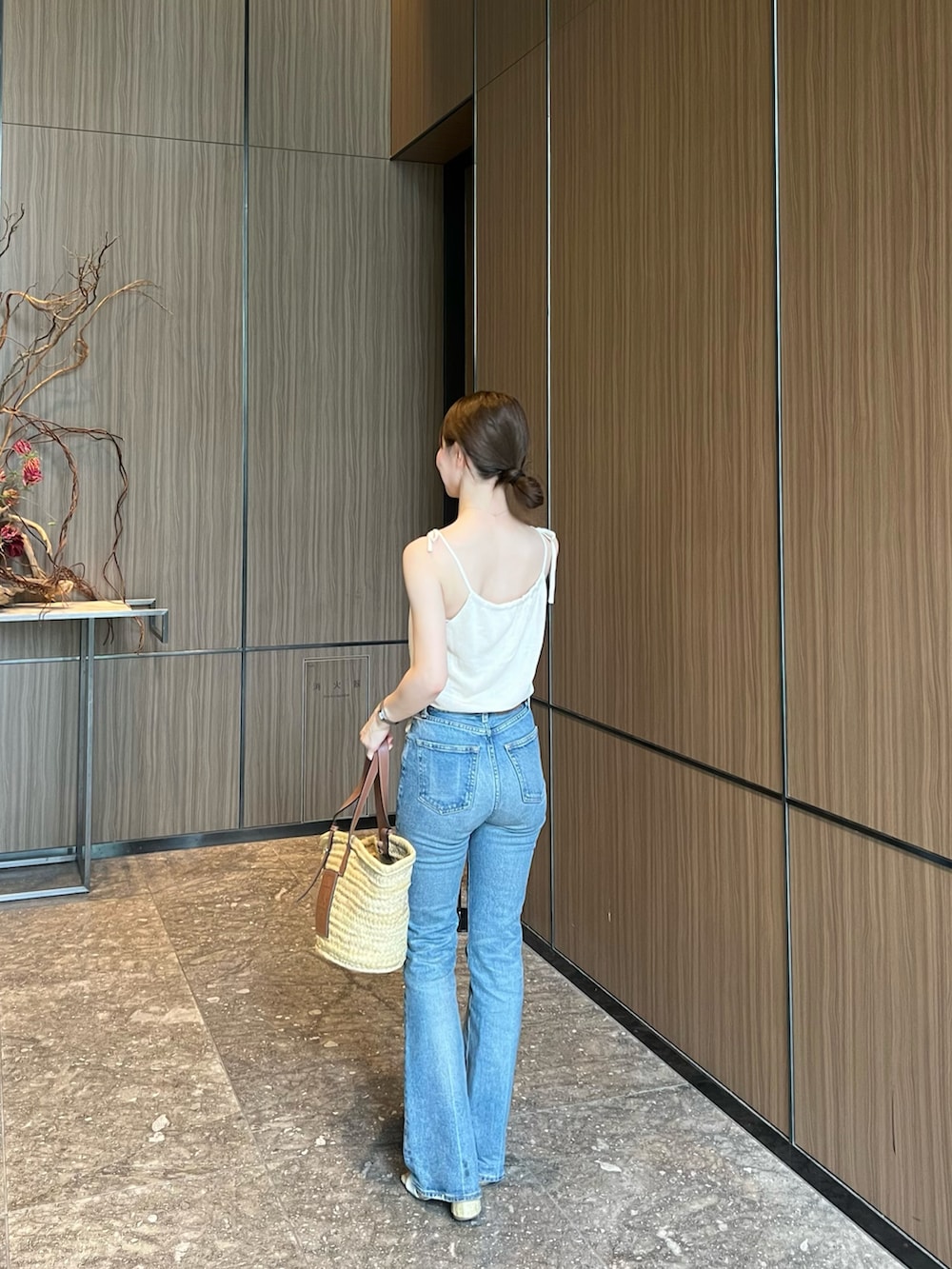 ブルー系のデニムパンツ、ベージュ系のかごバッグ、ホワイト系のサンダルを着用したレディースの夏コーディネートの3枚目の写真