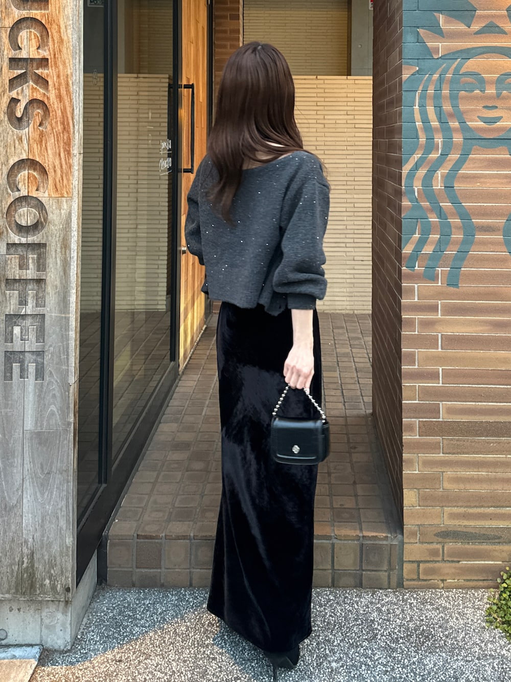 ブラック系のワンピース、グレー系のカーディガン/ボレロ、ブラック系のブーツを着用したレディースの冬コーディネートの2枚目の写真