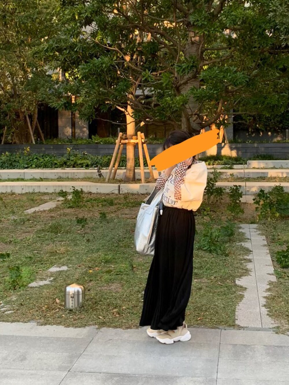 ブラック系のスカート、シルバー系のトートバッグ、ベージュ系のスニーカーを着用したレディースの秋コーディネートの2枚目の写真