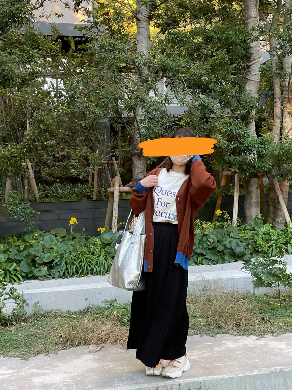 ブラック系のスカート、シルバー系のトートバッグ、ベージュ系のスニーカーを着用したレディースの秋コーディネートの3枚目の写真