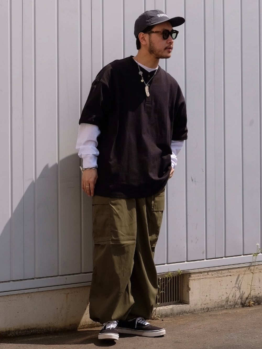 ブラック系のTシャツ/カットソー、グリーン系のカーゴパンツを着用したメンズの春コーディネートの2枚目の写真