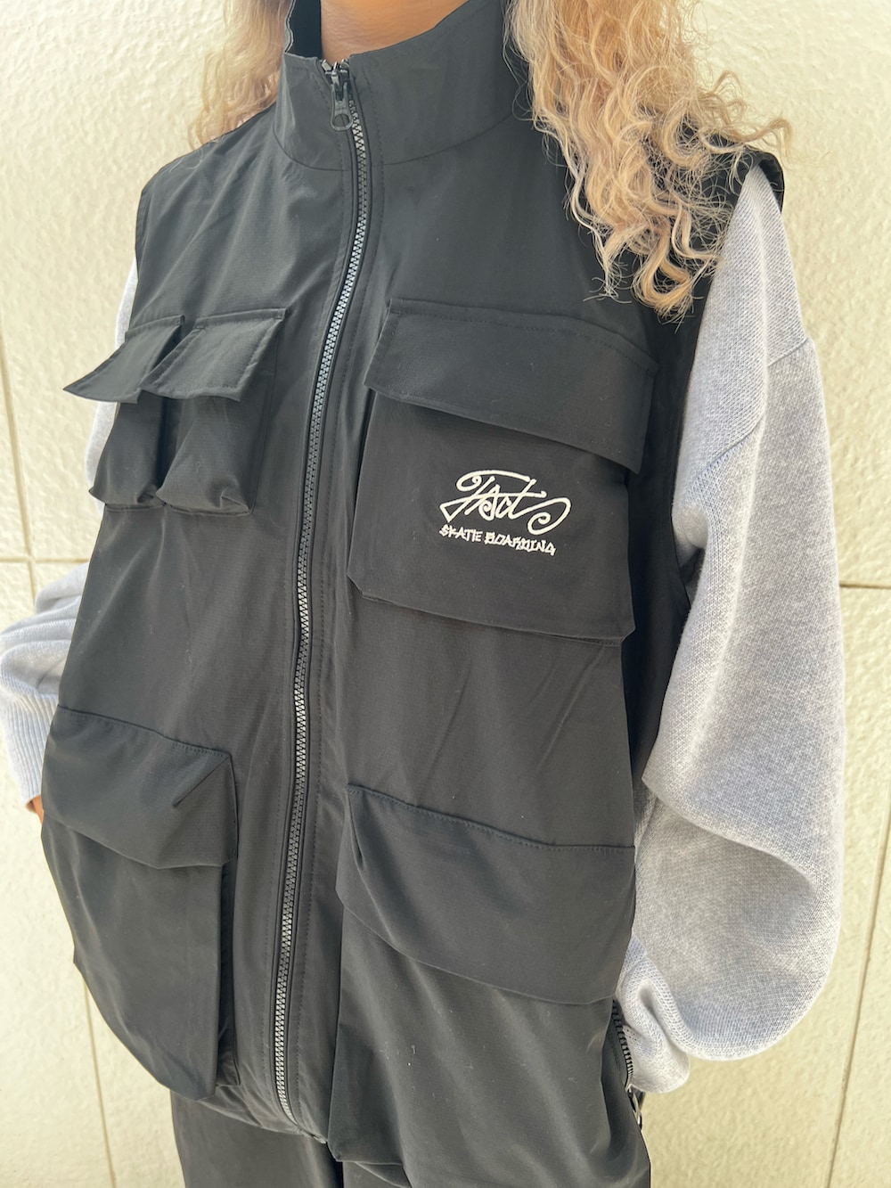 ブラック系のベスト、ブラック系のカーゴパンツ、グレー系のニット/セーターを着用したレディースの秋コーディネートの3枚目の写真