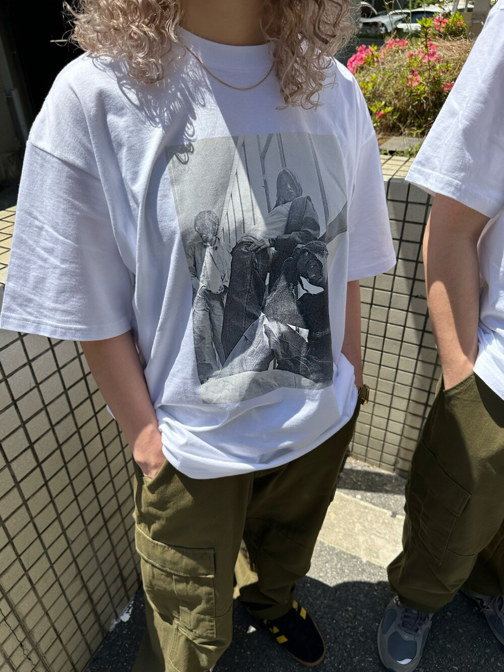 ホワイト系のTシャツ/カットソー、グリーン系のカーゴパンツ、ブラック系のスニーカーを着用したレディースの春コーディネートの3枚目の写真